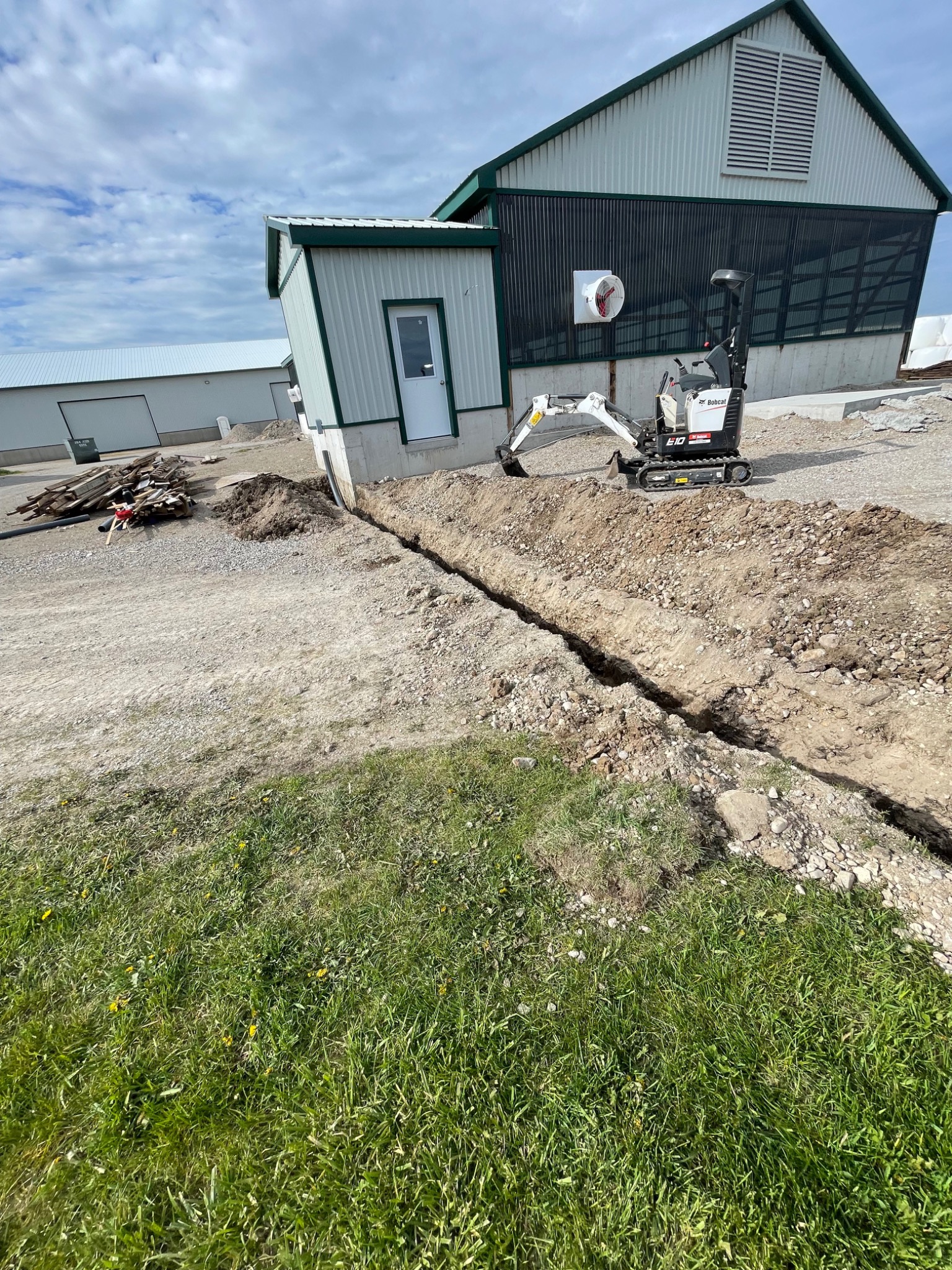 Utility trench excavated beside an agricultural building